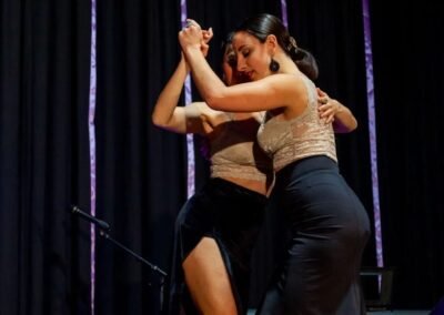 Una pareja de dos mujeres bailando tango en un escenario