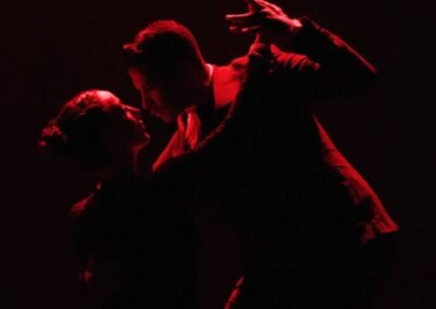 silueta de dos vailarines de tango con luz roja y fondo negro